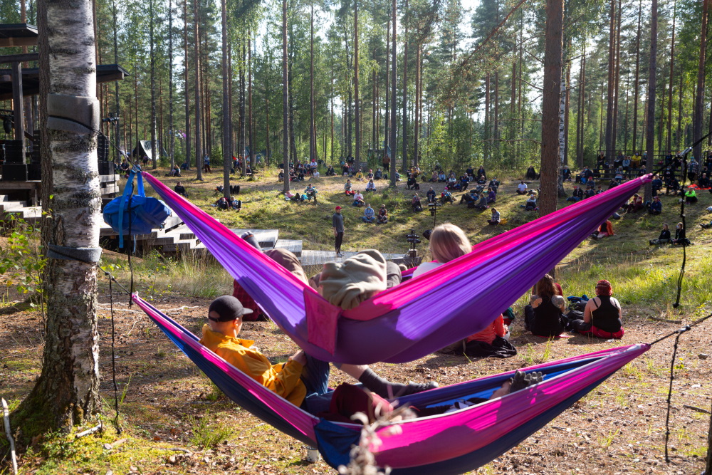 Pekka Hyysalo esiintymässä Johtajatulilla. Kuulijat istuvat metsässä ja riippumatoissa.