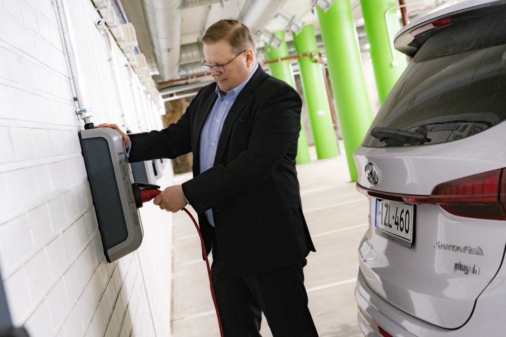 LähiTapiolan Matti Kiviniemi kiinnittää Hyundai Santa Fe Plug-in Hybridin latauskaapelia työpaikkansa latauslaitteeseen.