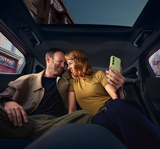 Hymyilevä pariskunta ottaa selfietä Hyundai IONIQ 3:n takapenkillä