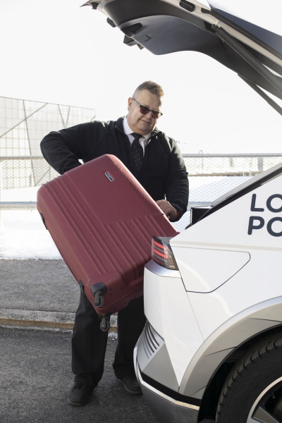 Taksinkuljettaja Kristian Linden nostaa asiakaan matkalaukkua IONIQ 5:n tavaratilaan.